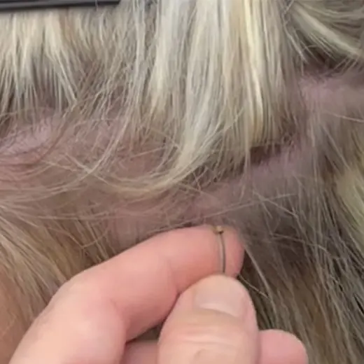 Stylist threading a small bead onto a fine section of the client's hair