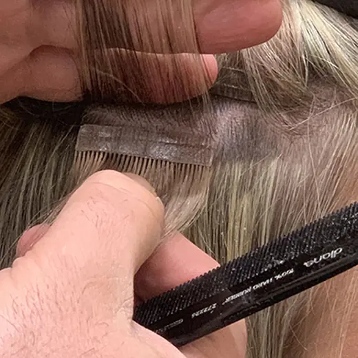 Placing the lower tape weft under a thin one-inch section of hair